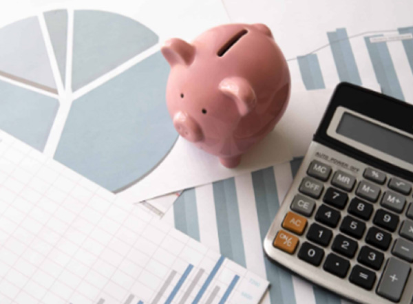 Hucha rosa y calculadora sobre gráficos financieros